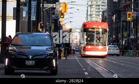 TTC Straßenbahn in Toronto Financial District als eine Frau fährt ein Fahrrad und Auto ist auf der Seite der Straße geparkt. Stockfoto