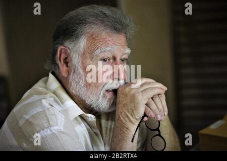 Älterer richtiger Mann mit runder Brille und grauem Bartdenken mit gekleppten Händen Schriftsteller Fotograf Philosoph Vater Großvater Stockfoto