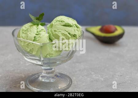 Nahaufnahme von hausgemachtem Avocado-Eis in einer Glasschale auf dunklem Hintergrund Stockfoto