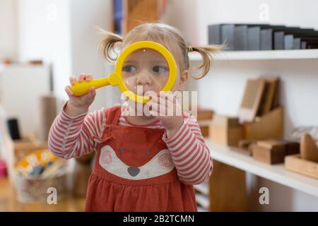 Kleinkind schaut durch Lupe Stockfoto