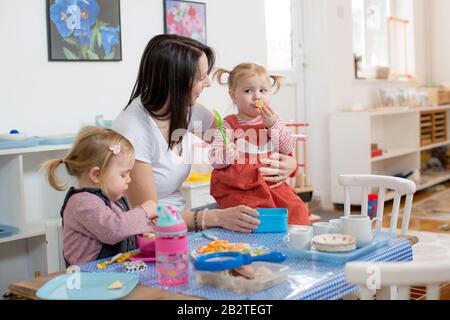 Lehrer und Kleinkinder an einem Tisch spielen vorgeben, Großbritannien Stockfoto