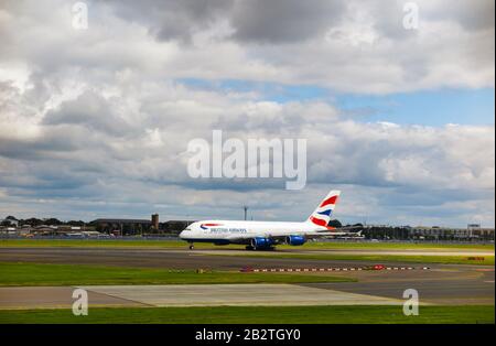 British Airways Airbus A380-861 im Firmenlivery Taxing auf der Landebahn des Flughafens London-Heathrow vom Terminal 3 aus unter dunklen düsteren Wolken gesehen Stockfoto