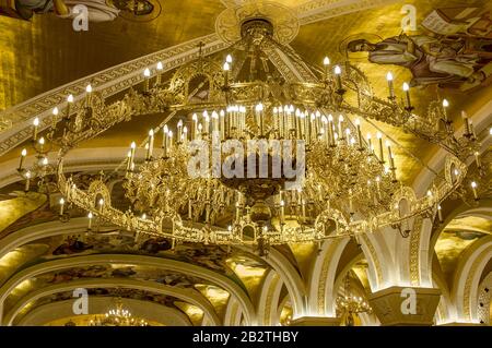 Belgrad, Serbien - 27. Februar 2020: Ein goldener Kronleuchter mit Freskos und Bögen in der Krypta der orthodoxen Kirche Sankt Sava in Belgrad, Serbien Stockfoto