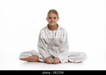 Sportliches Mädchen in keikogi sitzt auf dem Boden, weißer Hintergrund Stockfoto