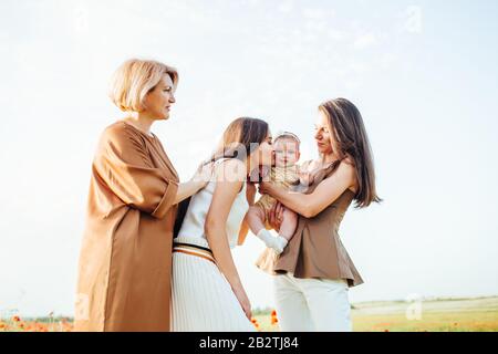 Drei Generationen. Großmutter, Töchter und Enkelin auf einer grünen Wiese. Stockfoto
