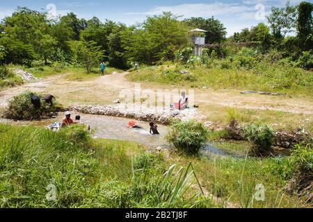 Frau wäscht Kleidung auf dem Fluss, Kinder spielen im Wasser, hinter einem menschenleeren UN-Stützpunkt, Blauhelm-Friedensmission Minustah, Mission des Nations Stockfoto