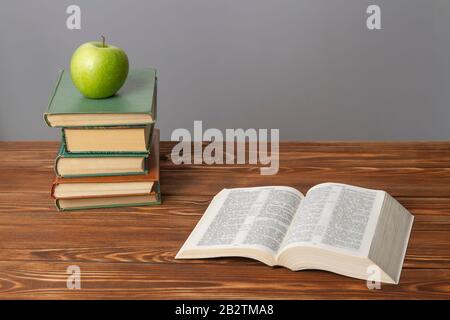 Buch auf dem Tisch geöffnet, grüner apfel, grauer Hintergrund. Stockfoto
