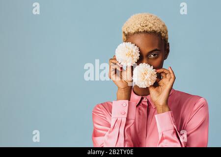 Porträt einer schönen jungen Frau, die zwei weiße rosafarbene Blumen hält Stockfoto