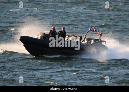 Ein Verteidigungsministerium, RHIB, vor Gourock am Firth of Clyde, fungiert als Eskorte zu einem ankommenden U-Boot der Royal Navy Trafalgar-Klasse. Stockfoto