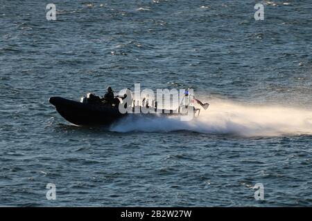 Ein Verteidigungsministerium, RHIB, vor Gourock am Firth of Clyde, fungiert als Eskorte zu einem ankommenden U-Boot der Royal Navy Trafalgar-Klasse. Stockfoto