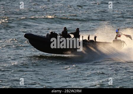 Ein Verteidigungsministerium, RHIB, vor Gourock am Firth of Clyde, fungiert als Eskorte zu einem ankommenden U-Boot der Royal Navy Trafalgar-Klasse. Stockfoto