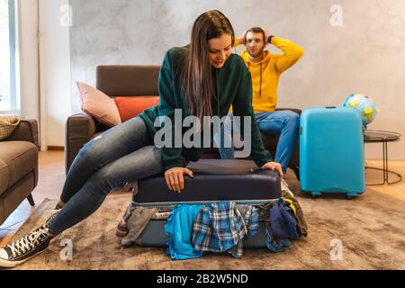 Das junge Paar bereitet die Koffer für die nächste Reise im Wohnzimmer zu Hause vor, Ferien rund um den Globus Stockfoto