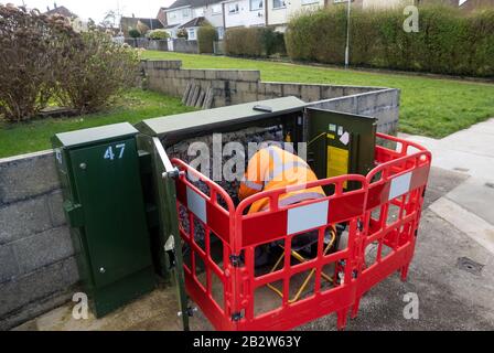 Openreach BT-Ingenieur arbeitet an einem grünen, von roten Barrieren umgebenen Schrank am Straßenrand Stockfoto