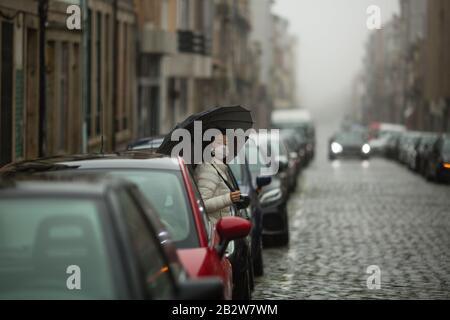 Asiatische Frau in antiviraler Maske steht bei trübem Wetter auf der Straße. Stockfoto