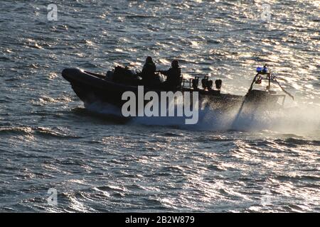 Ein Verteidigungsministerium, RHIB, vor Gourock am Firth of Clyde, fungiert als Eskorte zu einem ankommenden U-Boot der Royal Navy Trafalgar-Klasse. Stockfoto