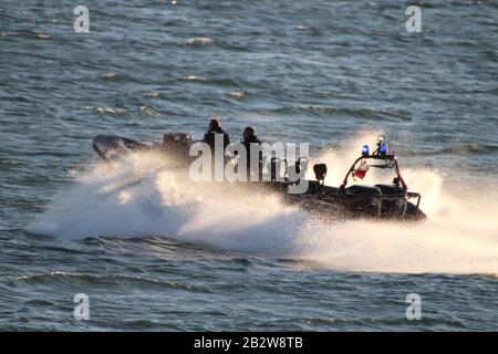 Ein Verteidigungsministerium, RHIB, vor Gourock am Firth of Clyde, fungiert als Eskorte zu einem ankommenden U-Boot der Royal Navy Trafalgar-Klasse. Stockfoto