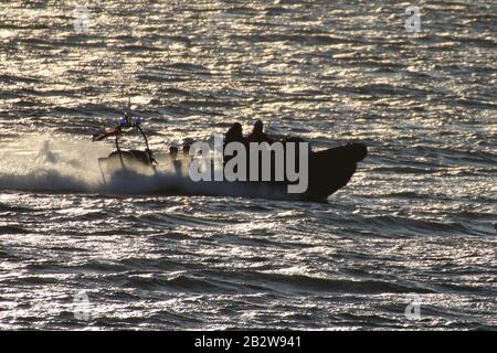 Ein Verteidigungsministerium, RHIB, vor Gourock am Firth of Clyde, fungiert als Eskorte zu einem ankommenden U-Boot der Royal Navy Trafalgar-Klasse. Stockfoto