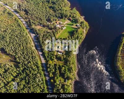 Blick auf den Fluss Kalix, Kalixalven, die Ortschaft Overkalix und den Sitz im schwedischen Kreis Norrbotten, mit Wald im sonnigen Sommertag, Blick auf die Drone Stockfoto