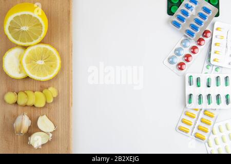 Zitrone, Ingwer und Kapelle gegen mehrfarbige Tabletten. Das Konzept der Wahl einer gesunden Ernährung im Gegensatz zur Einnahme von Medikamenten Stockfoto