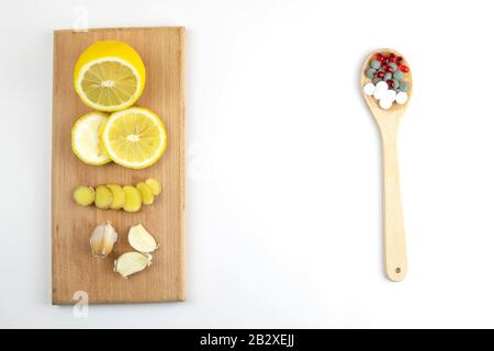 Zitrone, Ingwer und Kapelle gegen mehrfarbige Tabletten. Das Konzept der Wahl einer gesunden Ernährung im Gegensatz zur Einnahme von Medikamenten Stockfoto