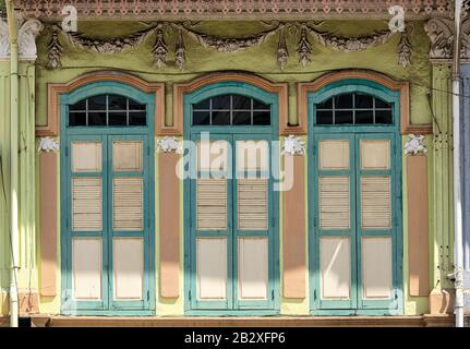 Farbenfrohes traditionelles Ladenhaus in Singapur mit antiken weißen und grünen Rollläden aus Holz und Bogenfenstern im historischen Geylang, Singapur Stockfoto