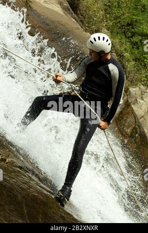 Erwachsene Mann Absteigend einer ecuadorianischen Wasserfall in die richtige Position Stockfoto