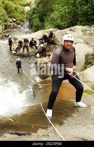 Gewachsener Mann, Der Einen ecuadorianischen Wasserfall In EINER Korrekten Position Absteigt Stockfoto