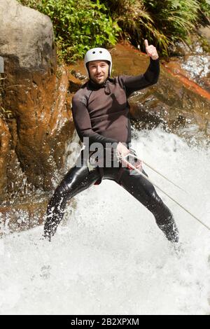 Erwachsene Mann Absteigend einer ecuadorianischen Wasserfall in die richtige Position Stockfoto