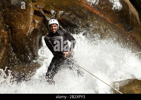 Erwachsene Mann Absteigend einer ecuadorianischen Wasserfall in die richtige Position Stockfoto