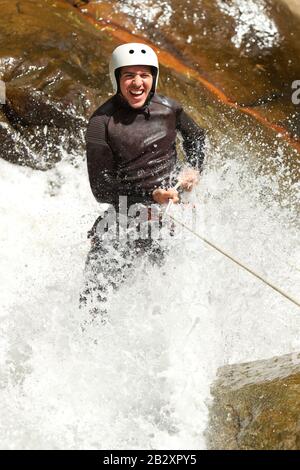 Erwachsene Mann Absteigend einer ecuadorianischen Wasserfall in die richtige Position Stockfoto