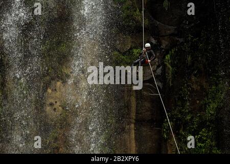 Erwachsene Mann Absteigend einer ecuadorianischen Wasserfall in die richtige Position Stockfoto