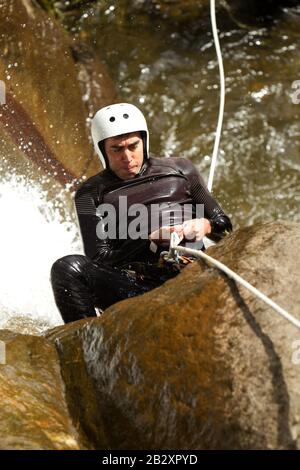 Erwachsene Mann Absteigend einer ecuadorianischen Wasserfall in die richtige Position Stockfoto