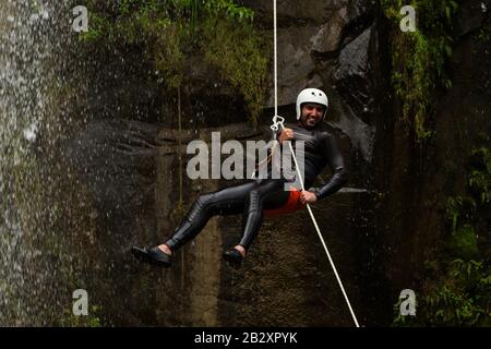 Erwachsene Mann Absteigend einer ecuadorianischen Wasserfall in die richtige Position Stockfoto