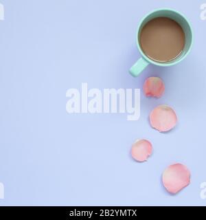 Tasse Kaffee mit Rosenblatt auf pastellviolettem Hintergrund. Draufsicht, Kopierraum Stockfoto