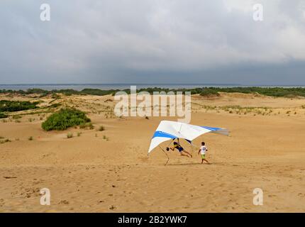 Der Schüler bereitet sich mit einem Lehrer der Kitty Hawk Kites Drachengleitschule auf den Sanddünen auf die Landung vor Stockfoto