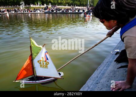 Alltag in Frankreich: Kind schiebt ein spielzeug-segelboot auf den Ententeich in Jardin du Luxembourg, eine französische Tradition. Rive Gauche, Paris, Franc, Europa Stockfoto