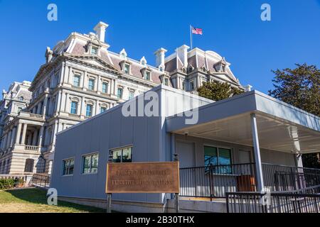 Schild für das Eisenhower Executive Office Building am vorderen Besuchereingang, hinten an einem klaren Tag zu sehen. Stockfoto