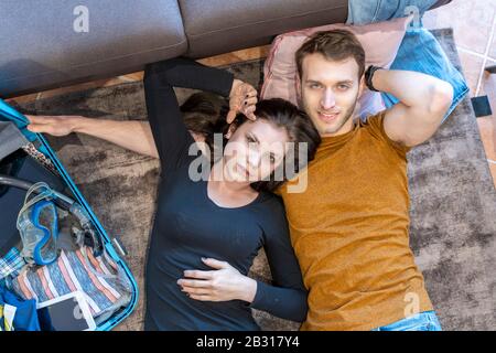 Liebendes Paar entspannt sich zu Hause auf dem Boden unter den Koffern, bevor es in den Urlaub geht Stockfoto