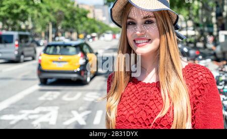 Glückliches, wunderschönes blondes Mädchen mit Strohhut, das die Stadt besucht, Taxi im Hintergrund. Tourismus- und Urlaubskonzept. Stockfoto