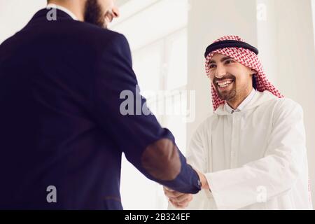 Handschlag arabischer und europäischer Geschäftsleute im Büro. Stockfoto
