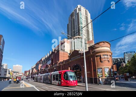 Urbane Szene einer roten Straßenbahn und der Market City in Hay St. in Sydney, Australien. Stockfoto