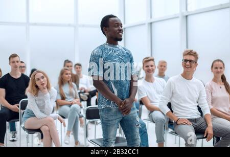 Lächelnder Kerl, der während des Seminars Fragen des Sprechers beantwortet Stockfoto