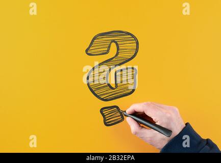 Draufsicht des Mannes, der den Filzstift hält und großes Fragezeichen auf orangefarbenem Hintergrund zeichnet Stockfoto