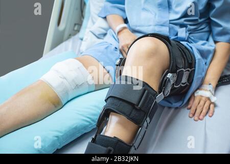 Patienten in Asien mit Knieauflage zur Bandkomprimierung unterstützen Verletzungen auf dem Bett im Pflegekrankenhaus.Gesundheitswesen und medizinische Unterstützung. Stockfoto