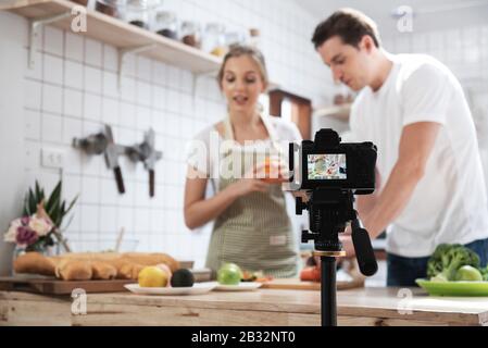 Professionelle digitale spiegellose Kamera Aufnahme Video-Blog von fröhlichen kaukasischen Paar Kochen in der Küche Zimmer. Stockfoto