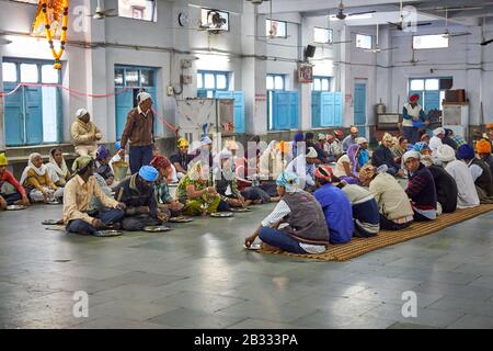 Männer, die in der Gemeinschaftsküche im Shish Ganj Gurudwara Sikh Tempel in Old Delhi, Delhi, Indien essen Stockfoto