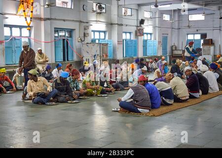 Männer, die in der Gemeinschaftsküche im Shish Ganj Gurudwara Sikh Tempel in Old Delhi, Delhi, Indien essen Stockfoto