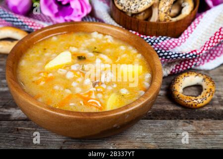 Rassolnik-Suppe in einem Holzteller und Bagels. Traditionelle russische Suppe. Stockfoto