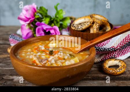 Rassolnik-Suppe in einem Holzteller und Bagels. Traditionelle russische Suppe. Stockfoto