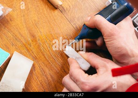 Der Meister schließt den Kratzer ab, die Wiederherstellung von Laminatparkett und Holzmöbel aus der Nähe. Stockfoto